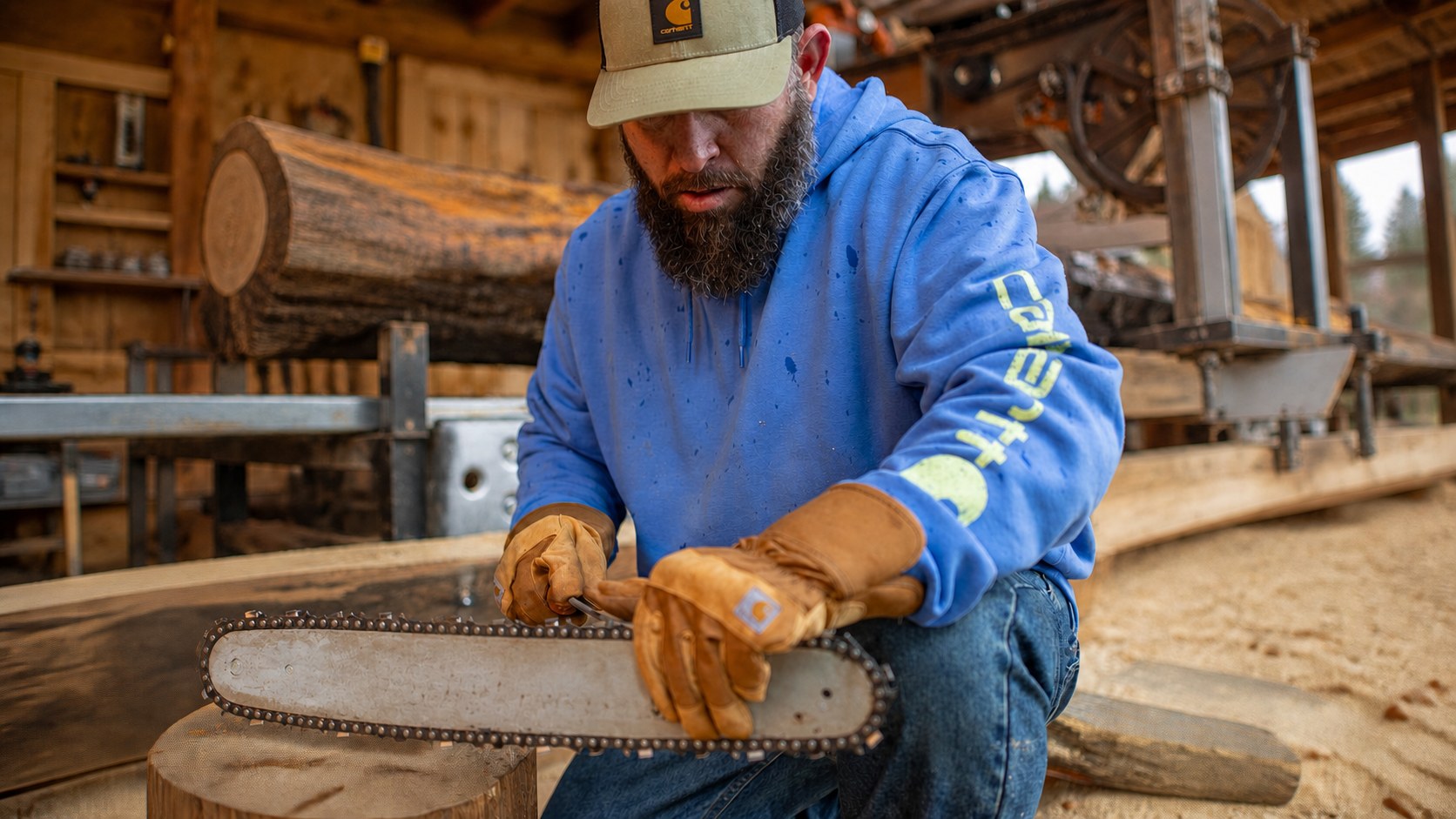 Worker in Carhartt clothing maintaining a chainsaw